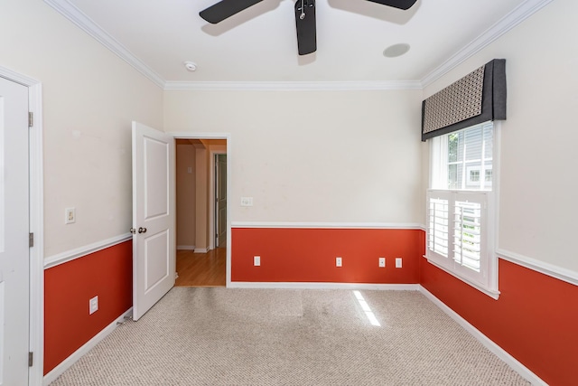 carpeted spare room featuring ornamental molding, a ceiling fan, baseboards, and a smoke detector