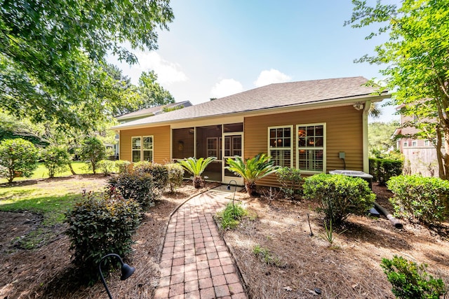 back of property with a sunroom and roof with shingles