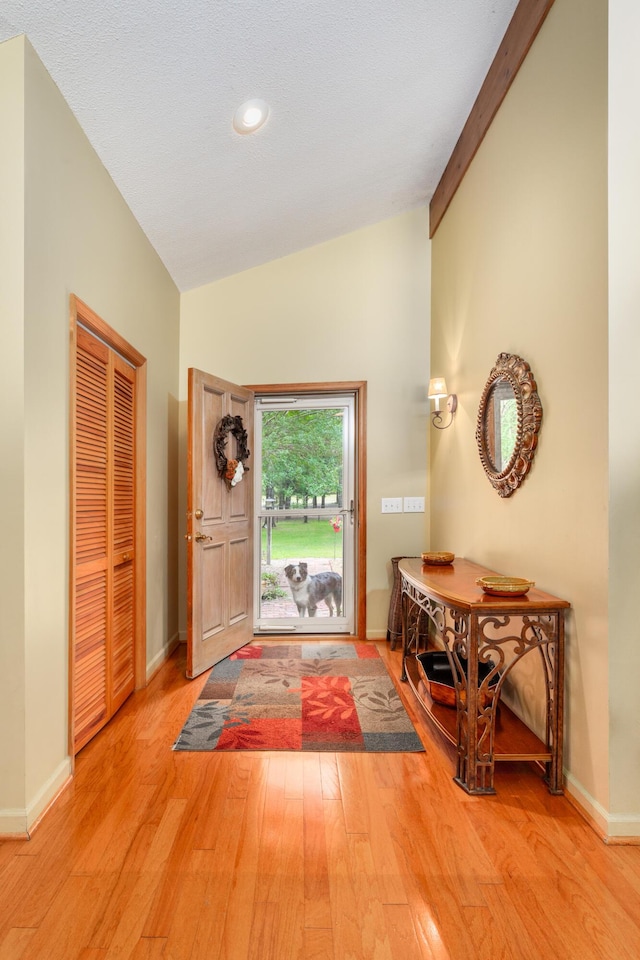 entrance foyer with vaulted ceiling with beams and light hardwood / wood-style floors