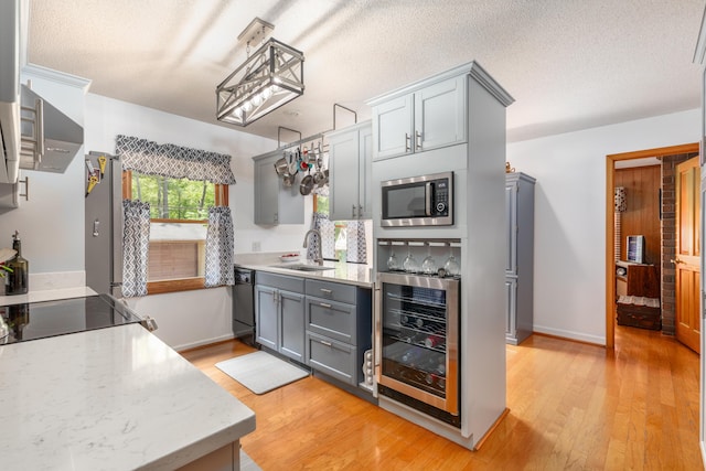 kitchen featuring sink, gray cabinetry, black dishwasher, beverage cooler, and light wood-type flooring