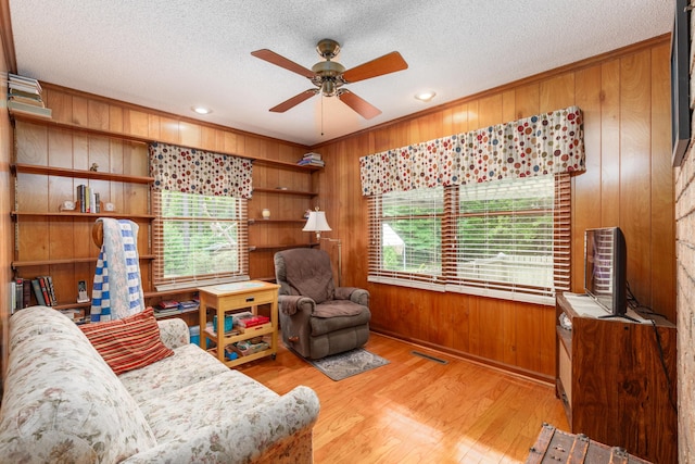 living room with wooden walls, light hardwood / wood-style floors, and a textured ceiling