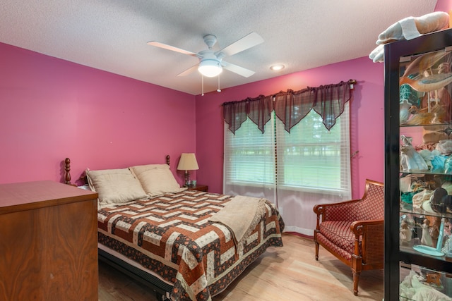 bedroom featuring ceiling fan, a textured ceiling, and light wood-type flooring