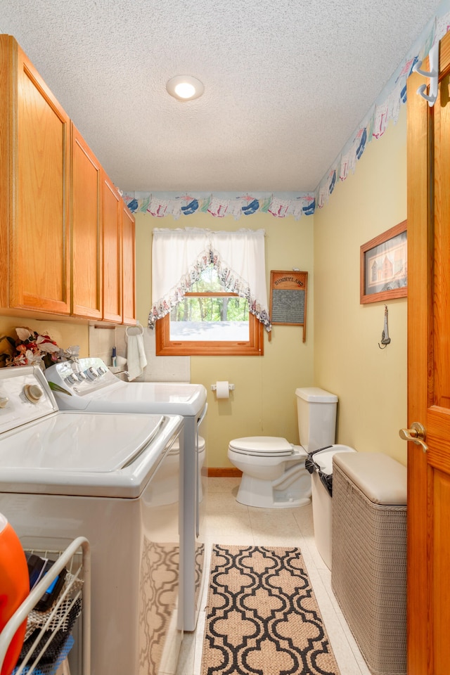 washroom with light tile patterned floors, a textured ceiling, and washing machine and clothes dryer