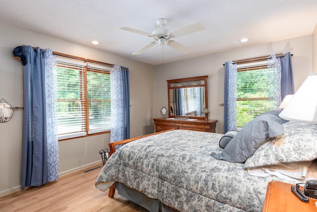 bedroom with ceiling fan, a textured ceiling, and light hardwood / wood-style flooring