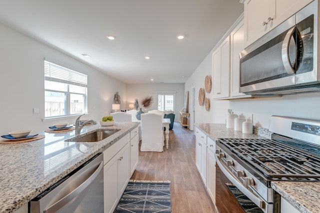 kitchen featuring light stone counters, sink, white cabinets, and stainless steel appliances