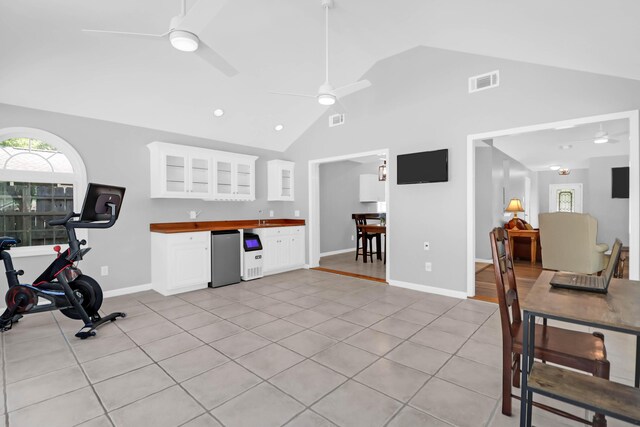interior space featuring a ceiling fan, visible vents, a sink, high vaulted ceiling, and light tile patterned flooring
