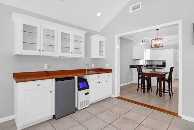 kitchen featuring visible vents, an inviting chandelier, lofted ceiling, fridge, and a sink