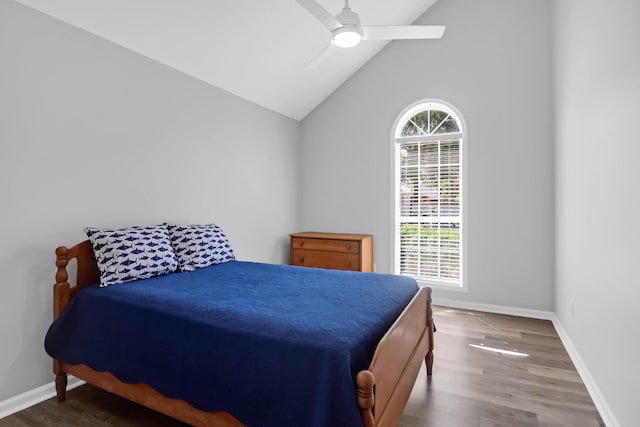 bedroom with baseboards, ceiling fan, wood finished floors, and lofted ceiling