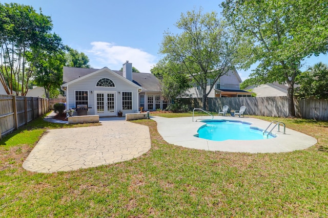 view of pool featuring a yard, a fenced in pool, french doors, and a patio area