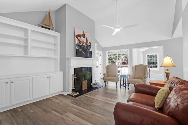 living area with a high end fireplace, high vaulted ceiling, ceiling fan, and wood finished floors