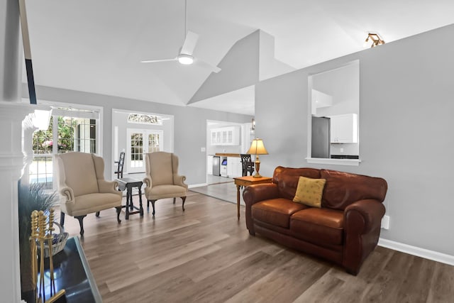 living room with baseboards, a ceiling fan, wood finished floors, and high vaulted ceiling