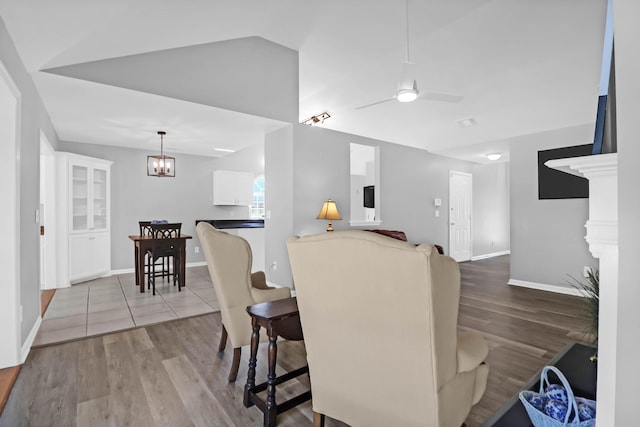 dining space featuring baseboards, wood finished floors, and ceiling fan with notable chandelier