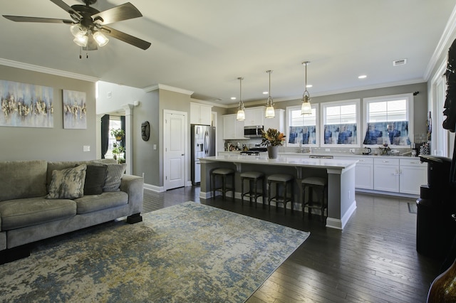 living room with dark hardwood / wood-style floors, ceiling fan, ornamental molding, and sink