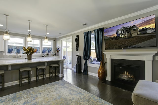 kitchen featuring pendant lighting, dark hardwood / wood-style floors, crown molding, and a kitchen breakfast bar