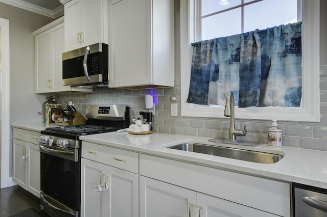 kitchen with white cabinets, stainless steel appliances, light stone countertops, and sink