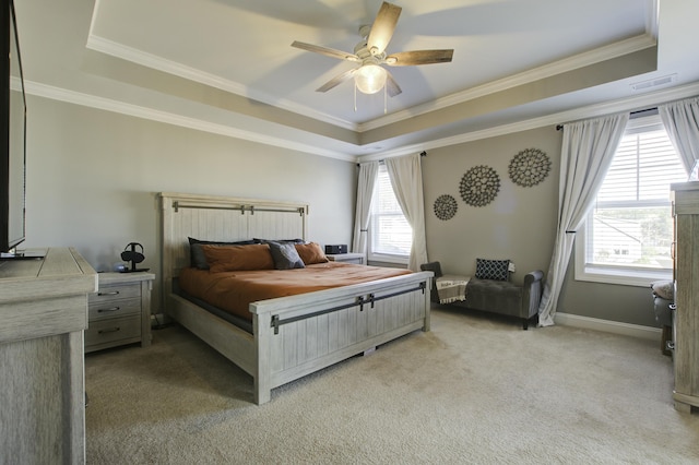 bedroom featuring ceiling fan, crown molding, light carpet, and a tray ceiling