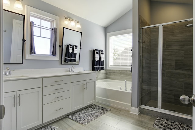 bathroom featuring vanity, plus walk in shower, a healthy amount of sunlight, and vaulted ceiling