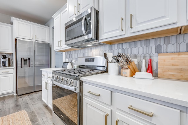 kitchen featuring white cabinets, decorative backsplash, light wood-type flooring, light stone countertops, and appliances with stainless steel finishes