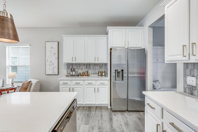 kitchen featuring white cabinetry, hanging light fixtures, tasteful backsplash, light hardwood / wood-style floors, and appliances with stainless steel finishes