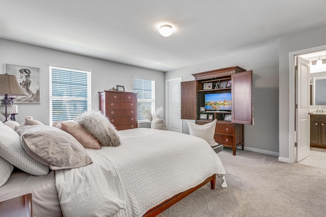 bedroom with ensuite bathroom and light carpet