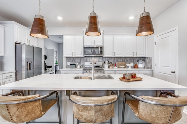 kitchen with a breakfast bar area, pendant lighting, an island with sink, and stainless steel appliances