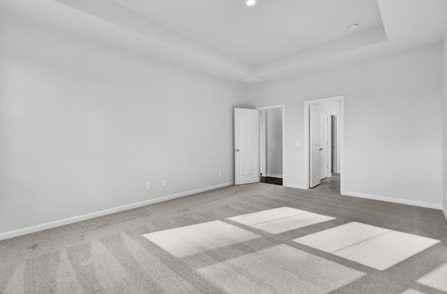 unfurnished bedroom with a tray ceiling and carpet