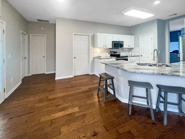 kitchen with visible vents, a kitchen bar, dark wood-style floors, stainless steel appliances, and a sink