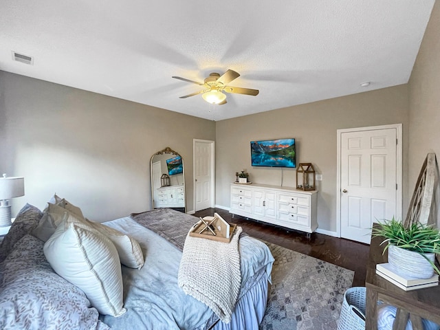 bedroom featuring baseboards, visible vents, dark wood finished floors, ceiling fan, and a textured ceiling