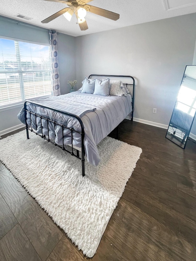 bedroom featuring visible vents, ceiling fan, baseboards, a textured ceiling, and dark wood-style flooring