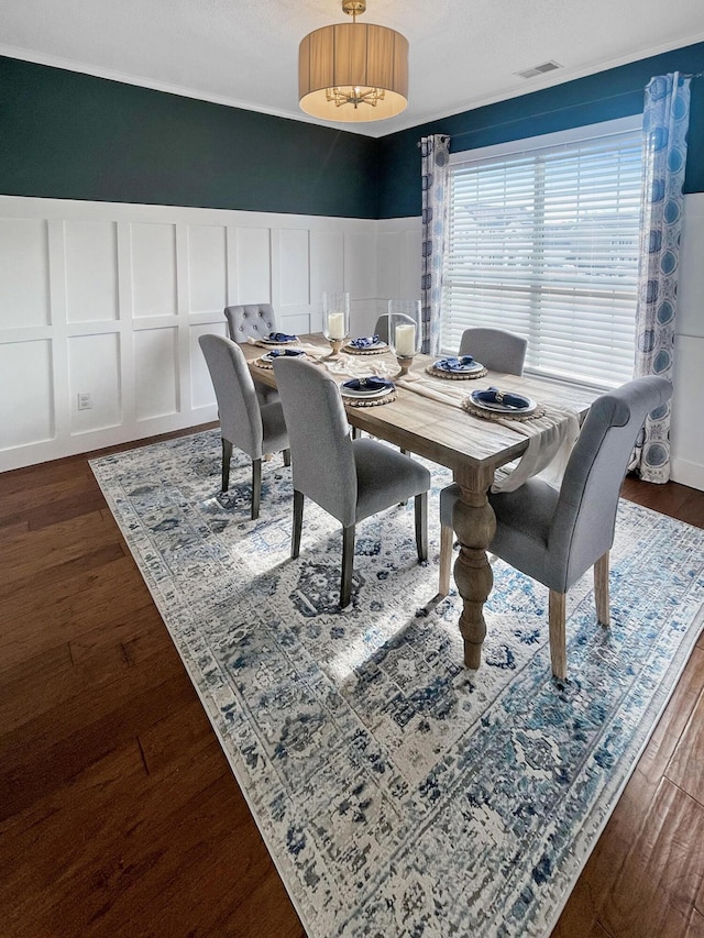 dining room featuring a decorative wall, visible vents, and dark wood-style flooring