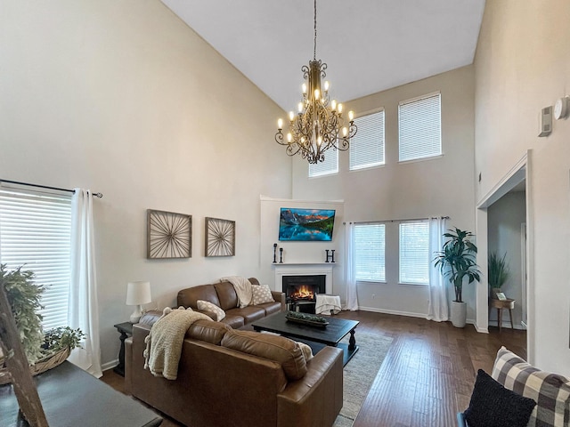 living area with high vaulted ceiling, baseboards, dark wood-style flooring, and a lit fireplace