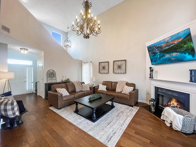 living room featuring hardwood / wood-style flooring, a fireplace with flush hearth, visible vents, and a towering ceiling