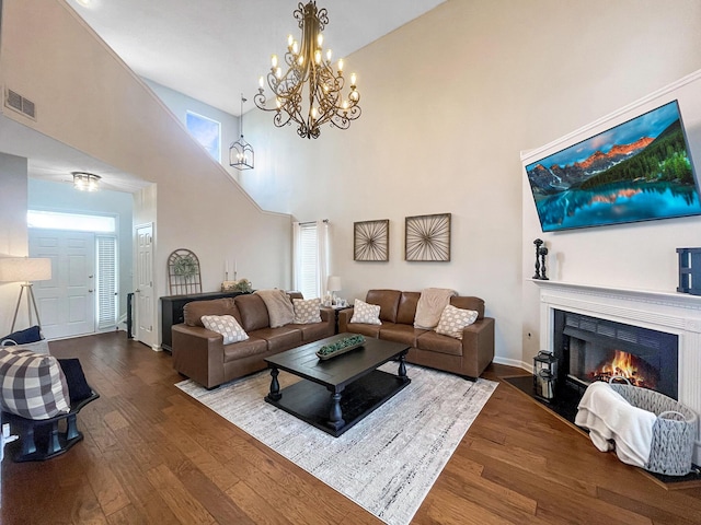 living area with a high ceiling, a fireplace with flush hearth, visible vents, and wood-type flooring