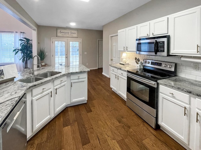 kitchen with tasteful backsplash, dark wood finished floors, french doors, stainless steel appliances, and a sink