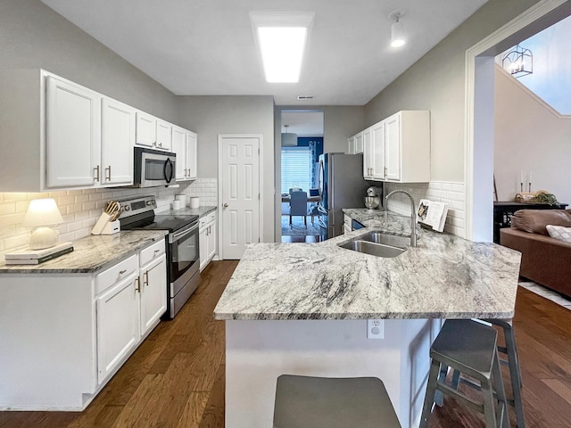 kitchen with a breakfast bar, a sink, stainless steel appliances, a peninsula, and light stone countertops