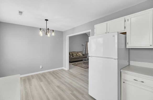 kitchen with light wood-type flooring, freestanding refrigerator, white cabinets, and baseboards