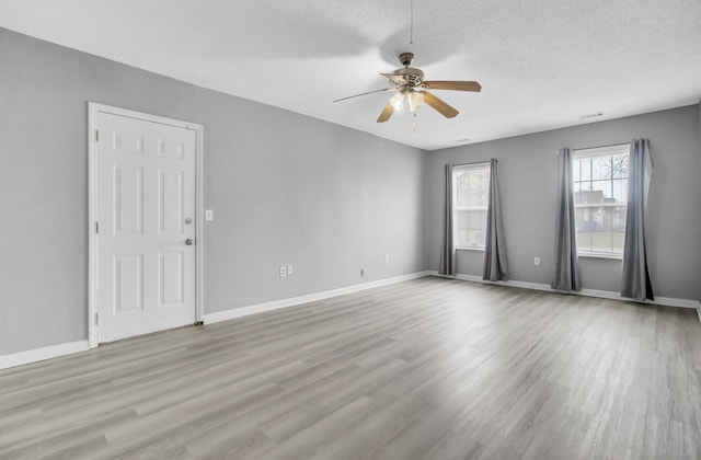 unfurnished room with a textured ceiling, ceiling fan, wood finished floors, and baseboards