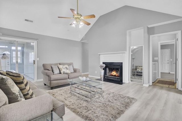 living room featuring a fireplace with flush hearth, ceiling fan, high vaulted ceiling, and wood finished floors