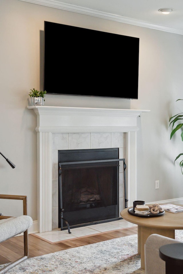 room details with ornamental molding, a tile fireplace, and wood finished floors