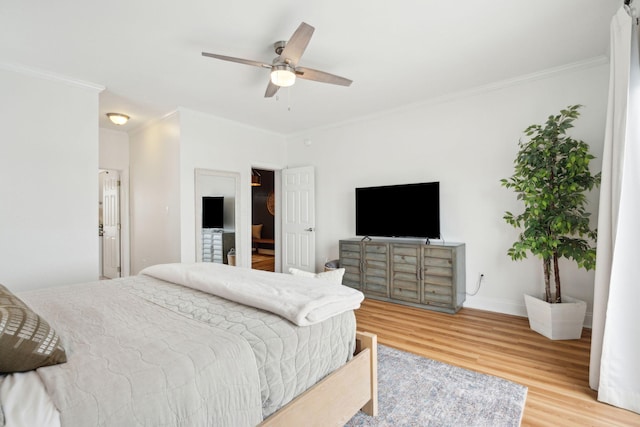 bedroom with ceiling fan, crown molding, baseboards, and wood finished floors