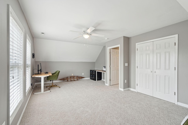 unfurnished office featuring carpet, lofted ceiling, visible vents, a ceiling fan, and baseboards