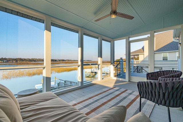 sunroom featuring lofted ceiling, ceiling fan, and a water view