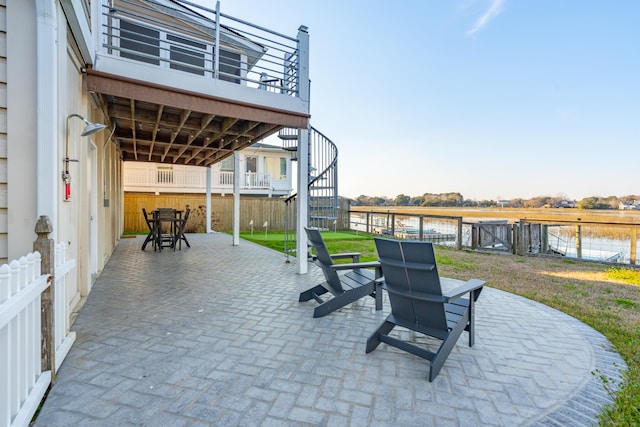 view of patio / terrace with stairway, a water view, and fence