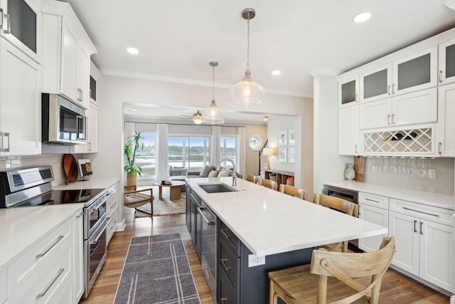 kitchen featuring white cabinets, an island with sink, a kitchen breakfast bar, stainless steel appliances, and a sink