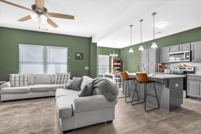 living room with wood-type flooring, sink, and ceiling fan with notable chandelier