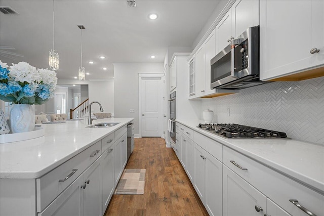 kitchen featuring stainless steel appliances, decorative light fixtures, white cabinetry, decorative backsplash, and dark hardwood / wood-style floors