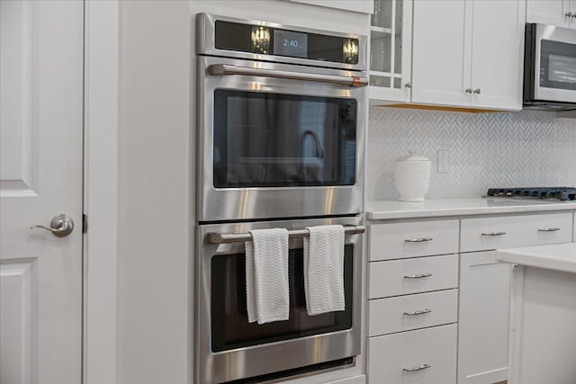 kitchen featuring stainless steel appliances, white cabinets, and tasteful backsplash