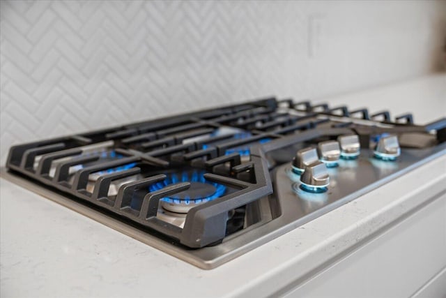 interior details featuring decorative backsplash and stainless steel gas stovetop