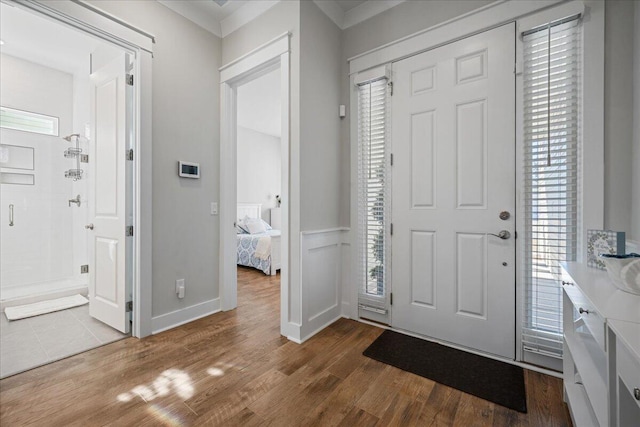 entryway featuring crown molding, wood-type flooring, and plenty of natural light