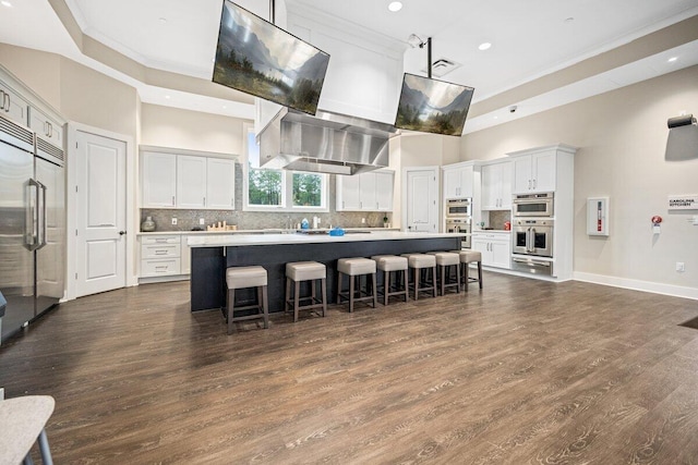 kitchen with extractor fan, a high ceiling, a kitchen bar, a kitchen island, and white cabinetry